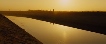 Movie still from “McFarland, USA” (2015), directed by Niki Caro – Two people are standing on the shore of a body of water at sunset; Extreme Wide shot, Low angle