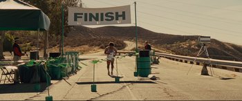 Movie still from “McFarland, USA” (2015), directed by Niki Caro – A person running a race on a road; Wide shot, Over the shoulder angle