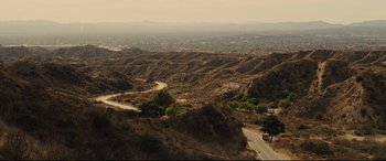 Movie still from “McFarland, USA” (2015), directed by Niki Caro – A view of a valley from a hill with a car on the road; Extreme Wide shot, High angle