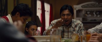 Movie still from “McFarland, USA” (2015), directed by Niki Caro – A man and a boy sitting at a dinner table eating food; Medium shot, Over the shoulder angle