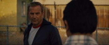 Movie still from “McFarland, USA” (2015), directed by Niki Caro – A man standing next to another man in front of a fence; Close Up shot, Over the shoulder angle