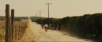 Movie still from “McFarland, USA” (2015), directed by Niki Caro – A group of people riding bikes down a dirt road; Extreme Wide shot, High angle