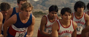Movie still from “McFarland, USA” (2015), directed by Niki Caro – A group of young men standing on top of a dirt field; Medium shot, Over the shoulder angle