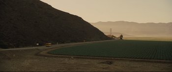 Movie still from “McFarland, USA” (2015), directed by Niki Caro – A road with a green field next to a hill; Extreme Wide shot, High angle