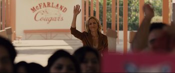 Movie still from “McFarland, USA” (2015), directed by Niki Caro – A woman waving at a crowd of people; Medium shot, Over the shoulder angle