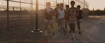 Movie still from “McFarland, USA” (2015), directed by Niki Caro – A group of young men running on a dirt field; Wide shot, High angle