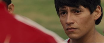 Movie still from “McFarland, USA” (2015), directed by Niki Caro – A young man's face in a field; Close Up shot, Over the shoulder angle