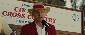 Movie still from “McFarland, USA” (2015), directed by Niki Caro – A man in a red jacket and a straw hat is holding a microphone; Close Up shot, Low angle
