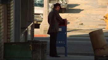 Movie still from “Mean Streets” (1973), directed by Martin Scorsese – A man standing next to a mailbox on the side of the street; Wide shot, Low angle