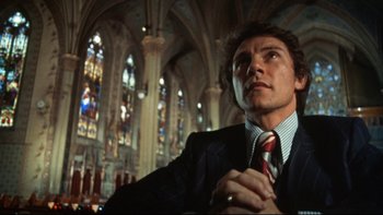 Movie still from “Mean Streets” (1973), directed by Martin Scorsese – A man wearing a suit and tie in a church; Close Up shot, Low angle