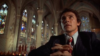 Movie still from “Mean Streets” (1973), directed by Martin Scorsese – A man wearing a suit and tie in a church; Close Up shot, Low angle