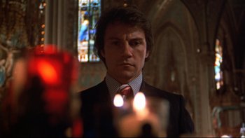 Movie still from “Mean Streets” (1973), directed by Martin Scorsese – A man standing in front of a candle in front of a stained glass window; Close Up shot, Low angle