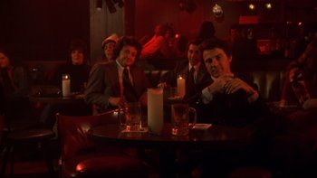 Movie still from “Mean Streets” (1973), directed by Martin Scorsese – A group of men sitting at a table in a bar; Wide shot, Low angle