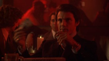 Movie still from “Mean Streets” (1973), directed by Martin Scorsese – A man in a suit and tie sitting in front of a candle; Medium shot, Over the shoulder angle