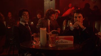 Movie still from “Mean Streets” (1973), directed by Martin Scorsese – A group of men sitting at a table with drinks; Medium shot, Low angle