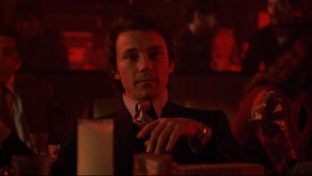 Movie still from “Mean Streets” (1973), directed by Martin Scorsese – A man sitting at a table in front of a glass of wine; Close Up shot, Low angle