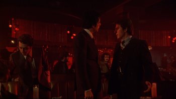 Movie still from “Mean Streets” (1973), directed by Martin Scorsese – Two men in suits talking to each other in a dark room; Medium shot, Over the shoulder angle