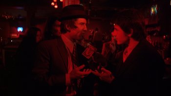 Movie still from “Mean Streets” (1973), directed by Martin Scorsese – A man in a suit talking to a woman in a suit and tie; Medium shot, Over the shoulder angle