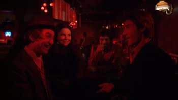 Movie still from “Mean Streets” (1973), directed by Martin Scorsese – A group of people sitting at a table in a room; Medium shot, Over the shoulder angle