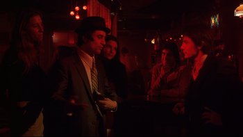 Movie still from “Mean Streets” (1973), directed by Martin Scorsese – A group of people standing in a dark room; Medium shot, Over the shoulder angle