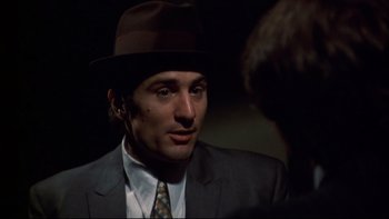 Movie still from “Mean Streets” (1973), directed by Martin Scorsese – A person wearing a suit and a hat; Close Up shot, Over the shoulder angle