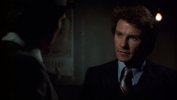 Movie still from “Mean Streets” (1973), directed by Martin Scorsese – A man wearing a suit and tie in a dark room; Close Up shot, Over the shoulder angle
