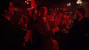 Movie still from “Mean Streets” (1973), directed by Martin Scorsese – A man in a suit and hat sitting at a bar; Wide shot, Over the shoulder angle