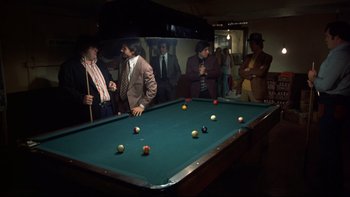 Movie still from “Mean Streets” (1973), directed by Martin Scorsese – A group of people standing around a pool table; Wide shot, High angle