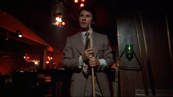Movie still from “Mean Streets” (1973), directed by Martin Scorsese – A man in a suit and tie holding a pool cue; Medium shot, Low angle