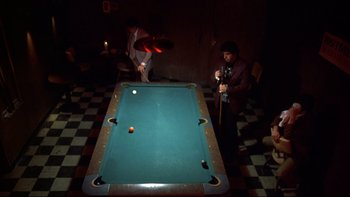 Movie still from “Mean Streets” (1973), directed by Martin Scorsese – Two men playing a game of billiards in the dark; Wide shot, High angle