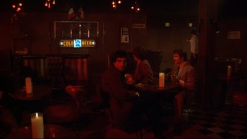 Movie still from “Mean Streets” (1973), directed by Martin Scorsese – A group of people sitting at a table in a room; Wide shot, Over the shoulder angle