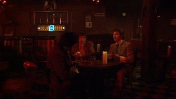 Movie still from “Mean Streets” (1973), directed by Martin Scorsese – A group of people sitting at a table in front of a candle; Wide shot, High angle