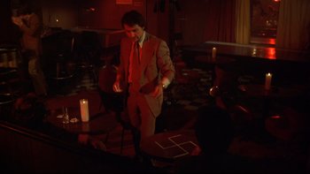 Movie still from “Mean Streets” (1973), directed by Martin Scorsese – A man standing in a room with candles; Wide shot, High angle