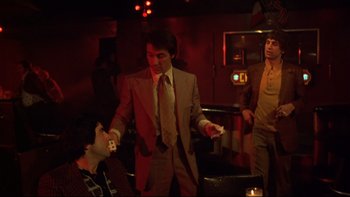 Movie still from “Mean Streets” (1973), directed by Martin Scorsese – A group of men standing in a dark room; Medium shot, Over the shoulder angle