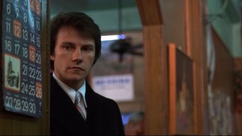 Movie still from “Mean Streets” (1973), directed by Martin Scorsese – A man wearing a suit and tie standing in front of a window; Close Up shot, Low angle