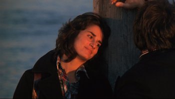 Movie still from “Mean Streets” (1973), directed by Martin Scorsese – A man with long brown hair leaning against a wooden pole; Close Up shot, High angle