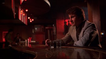 Movie still from “Mean Streets” (1973), directed by Martin Scorsese – A man sitting at a bar with two glasses of alcohol; Medium shot, Low angle