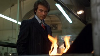 Movie still from “Mean Streets” (1973), directed by Martin Scorsese – A man standing next to a fire in front of a piano; Medium shot, Low angle