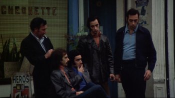 Movie still from “Mean Streets” (1973), directed by Martin Scorsese – A group of men standing next to each other on the street; Wide shot, High angle