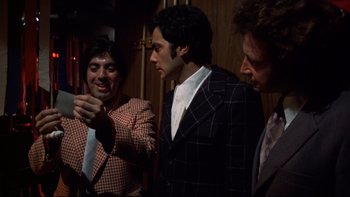 Movie still from “Mean Streets” (1973), directed by Martin Scorsese – A group of men standing next to each other in a room; Medium shot, Over the shoulder angle