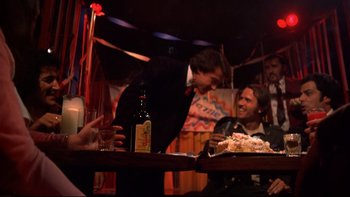 Movie still from “Mean Streets” (1973), directed by Martin Scorsese – A man standing at a table in front of a plate of food; Medium shot, Over the shoulder angle
