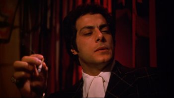 Movie still from “Mean Streets” (1973), directed by Martin Scorsese – A person wearing a suit and holding a cigarette; Close Up shot, Low angle