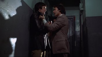 Movie still from “Mean Streets” (1973), directed by Martin Scorsese – Two men in a dark room , one of whom is holding a tie; Medium shot, Low angle