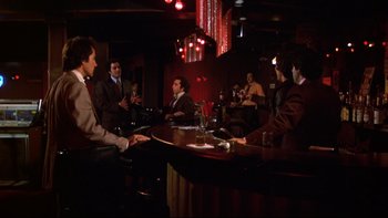 Movie still from “Mean Streets” (1973), directed by Martin Scorsese – A group of people sitting at a table in a room; Wide shot, High angle
