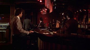 Movie still from “Mean Streets” (1973), directed by Martin Scorsese – A group of people sitting at a table in a bar; Wide shot, High angle