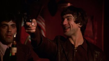 Movie still from “Mean Streets” (1973), directed by Martin Scorsese – A man holding a gun in his right hand; Close Up shot, Low angle
