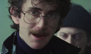 Movie still from “Meantime” (1983), directed by Mike Leigh – A person wearing glasses and a mustache; Close Up shot, Low angle