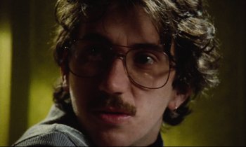 Movie still from “Meantime” (1983), directed by Mike Leigh – A person wearing glasses and a mustache; Close Up shot, Low angle