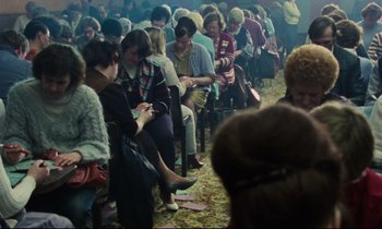 Movie still from “Meantime” (1983), directed by Mike Leigh – A group of people sitting in a large room; Medium shot, High angle
