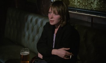 Movie still from “Meantime” (1983), directed by Mike Leigh – A woman sitting in a booth with a cigarette in her mouth; Close Up shot, High angle